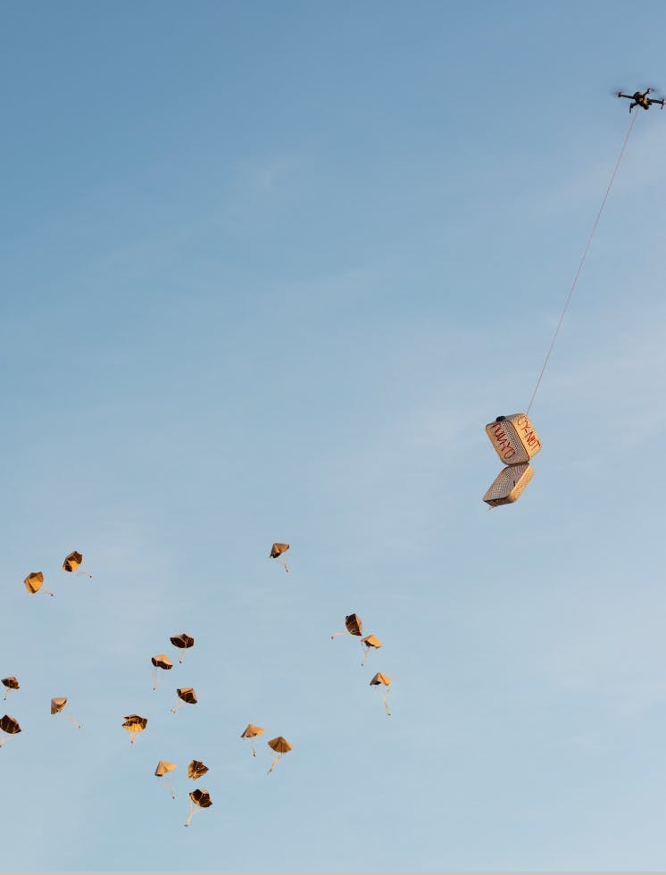 Small parachutes released from a basket in the sky.